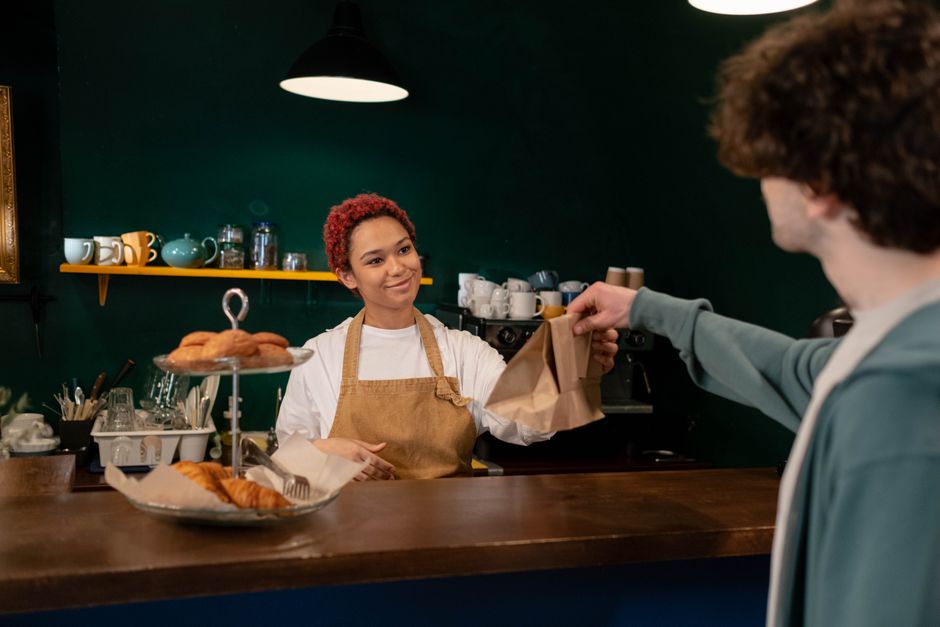 Baker som gir en pose med fersk bakst til en kunde