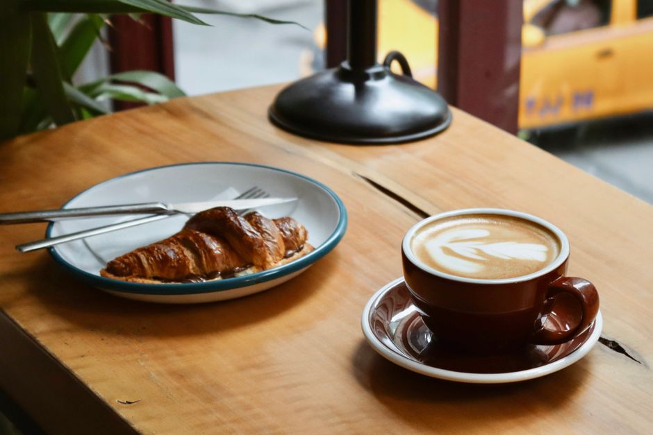 Croissant og kaffe ved et lyst kafévindu